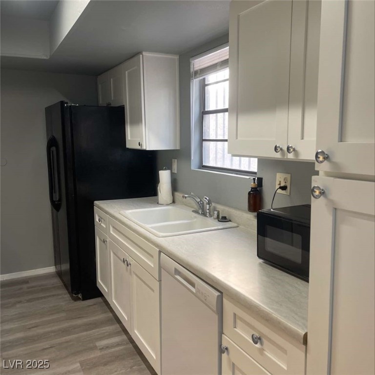 4640 Koval Lane, Unit 49A Las Vegas, NV 89109 - Photo 9 of 17 Kitchen featuring dishwasher, black microwave, a sink, and white cabinets