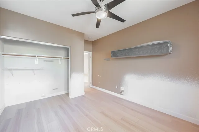 an empty room with a ceiling fan and wooden floor