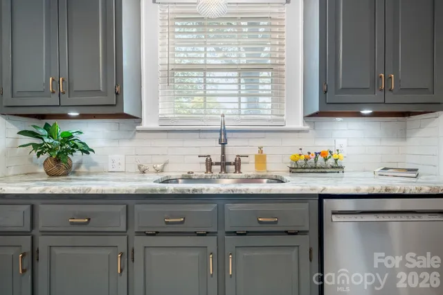 a kitchen with granite countertop stainless steel appliances white cabinets sink and granite counter tops