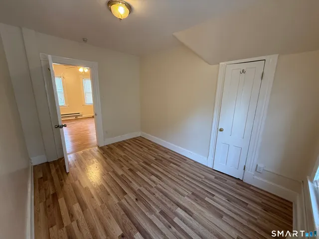 a view of an empty room with wooden floor and a window