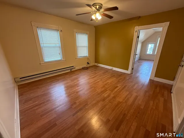 a view of an empty room with wooden floor and a window