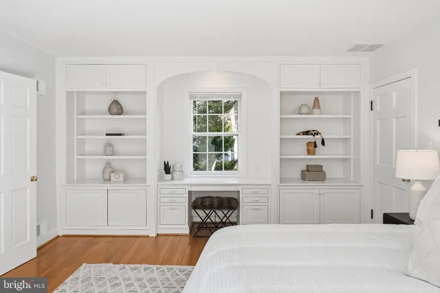 a spacious bedroom with a bed a table and painting