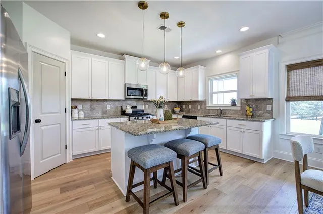 a kitchen with granite countertop white cabinets and stainless steel appliances