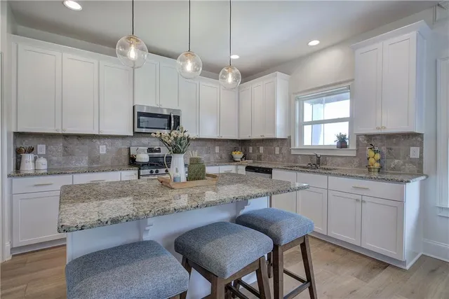 a kitchen with kitchen island granite countertop stainless steel appliances a stove sink microwave and cabinets