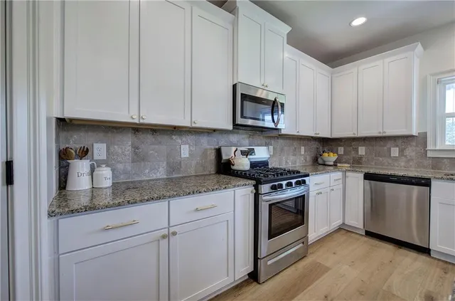 a kitchen with granite countertop white cabinets and a sink