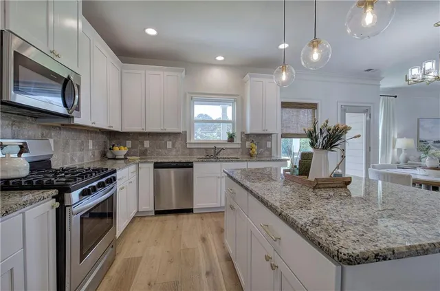 a kitchen with kitchen island a dining table chairs sink and cabinets