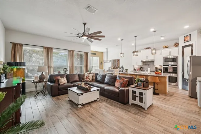 a living room with furniture large window and wooden floor