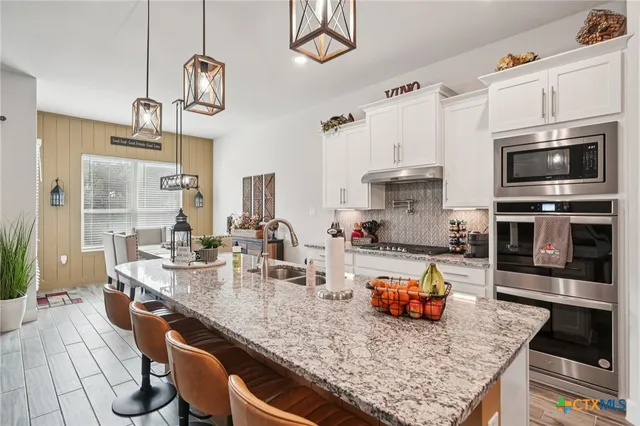 a kitchen with stainless steel appliances granite countertop a sink a stove and a refrigerator