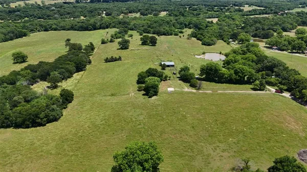 an aerial view of a houses with outdoor space and trees all around