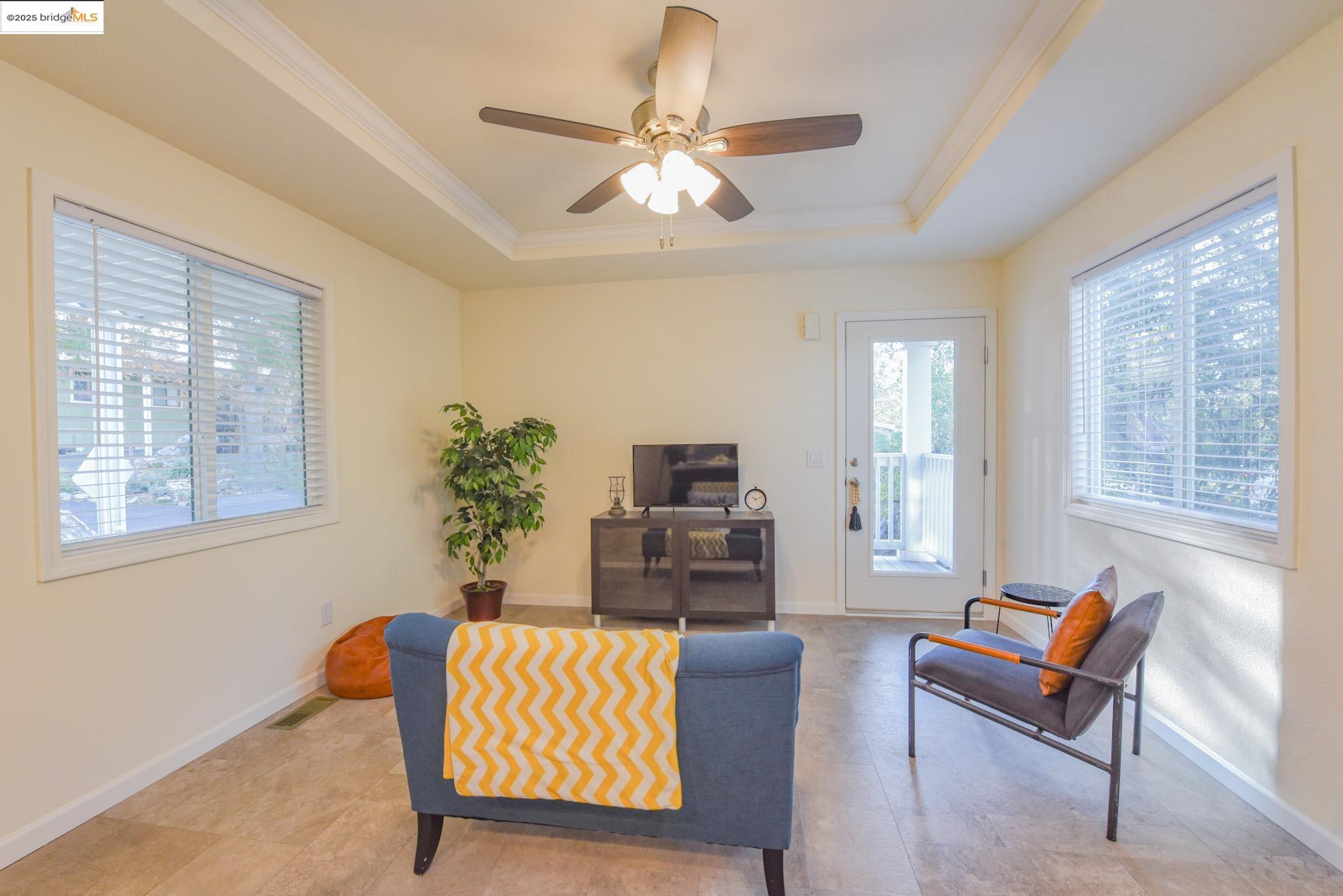 10956 Green Street Columbia, CA 95310 - Photo 25 of 45 Living area with a ceiling fan, a tray ceiling, and crown molding