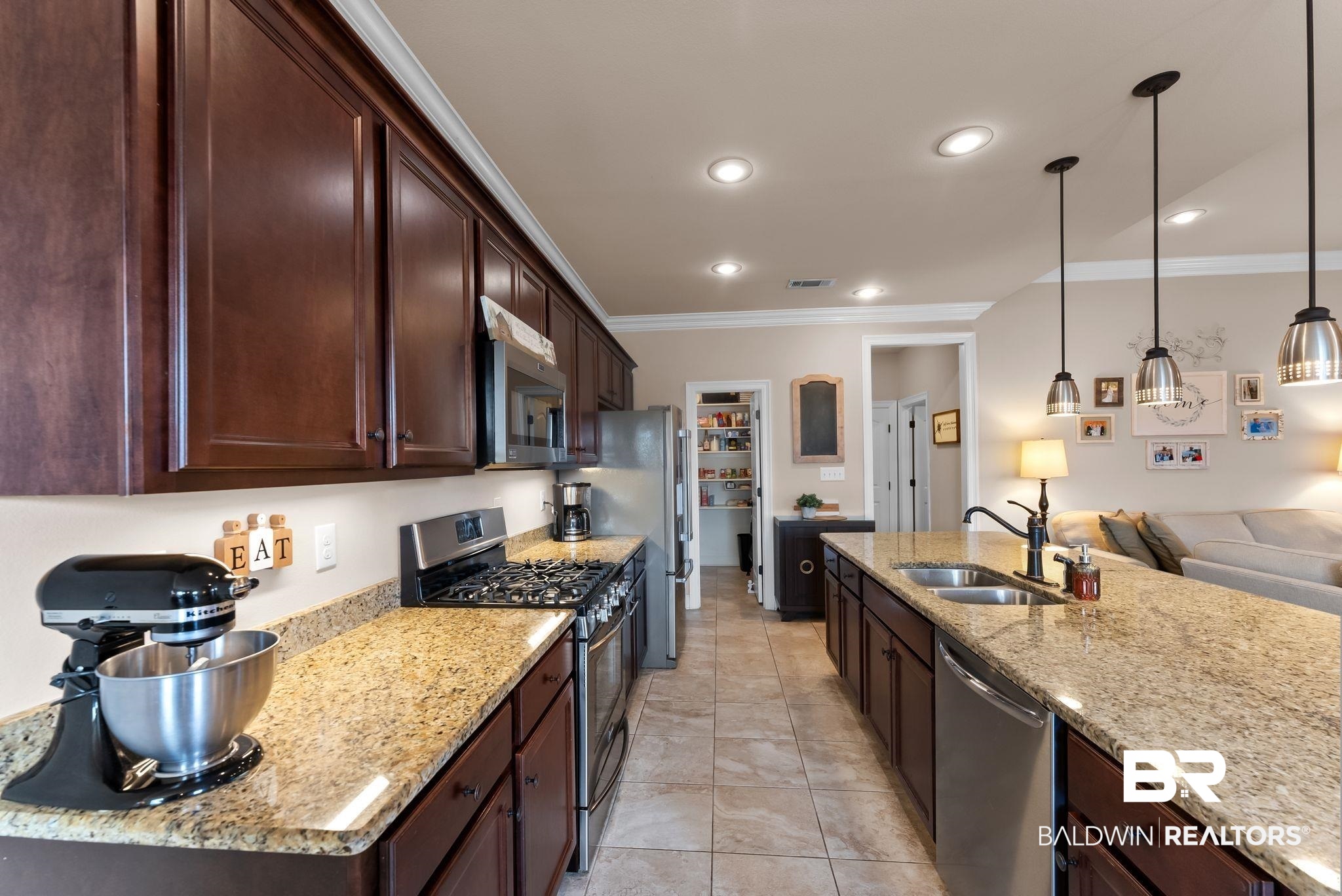 7015 Rocky Rd Loop Gulf Shores, AL 36542 - Photo 40 of 41 Kitchen with open floor plan, stainless steel appliances, dark wood finish cabinetry, crown molding, and light stone countertops
