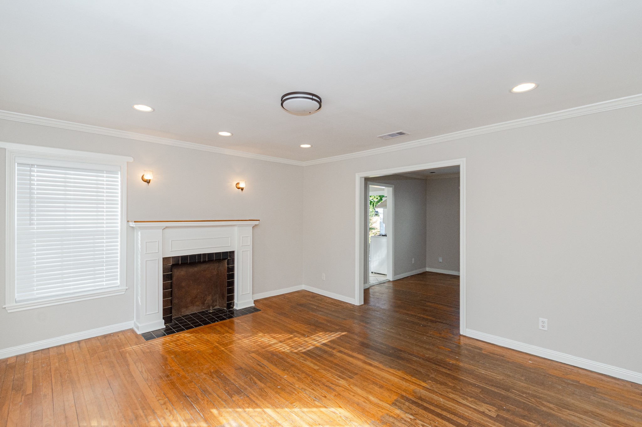 7447 Magnolia Street Houston, TX 77023 - Photo 4 of 38 a view of an empty room with wooden floor fireplace and a window