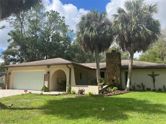 a front view of a house with a garden and trees