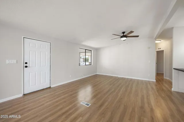 a view of empty room with wooden floor and fan