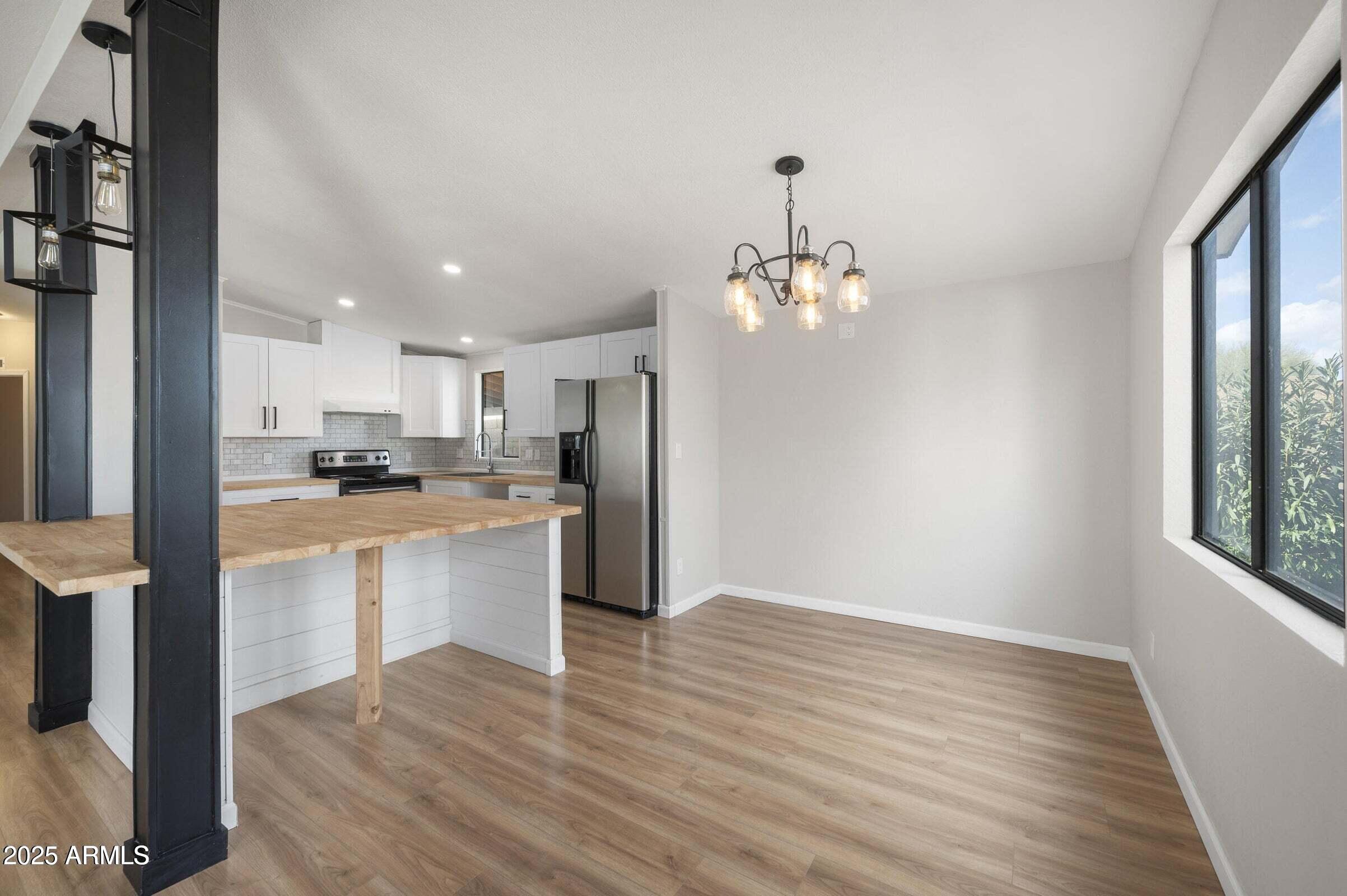 3500 South Tomahawk Road, Unit 126 Apache Junction, AZ 85119 - Photo 15 of 38 a large kitchen with kitchen island a sink dishwasher a refrigerator and white cabinets with wooden floor