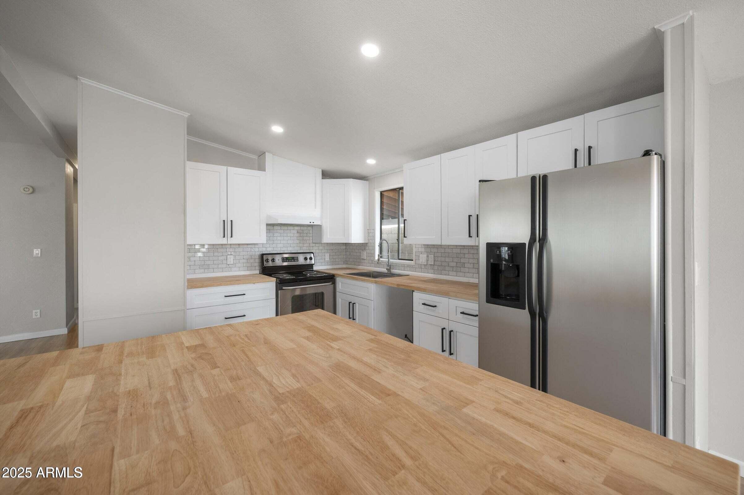 3500 South Tomahawk Road, Unit 126 Apache Junction, AZ 85119 - Photo 17 of 38 a kitchen with granite countertop a refrigerator sink and cabinets