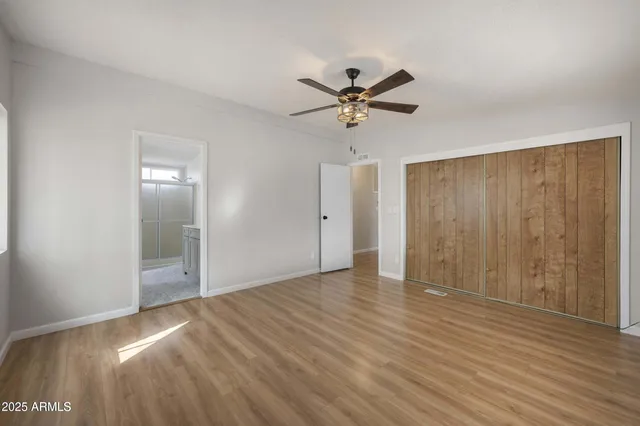 a view of empty room with wooden floor and fan
