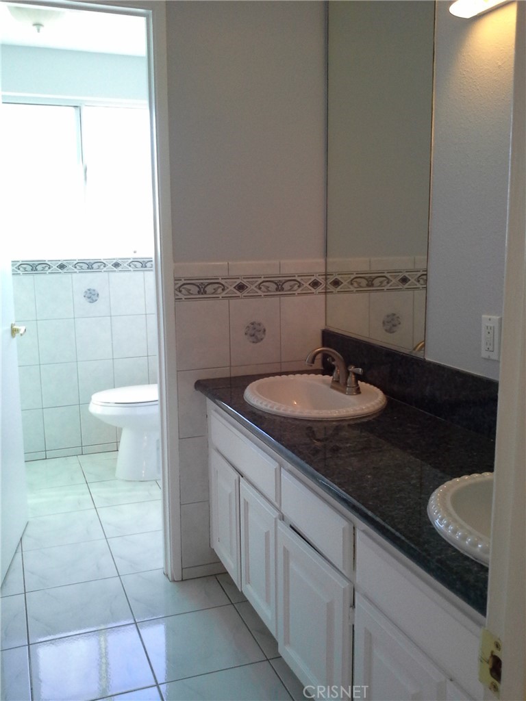 18918 Kinbrace Street Porter Ranch, CA 91326 - Photo 10 of 16 a bathroom with a granite countertop sink a toilet a mirror and a shower