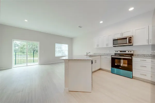 a kitchen with granite countertop a stove top oven and cabinets