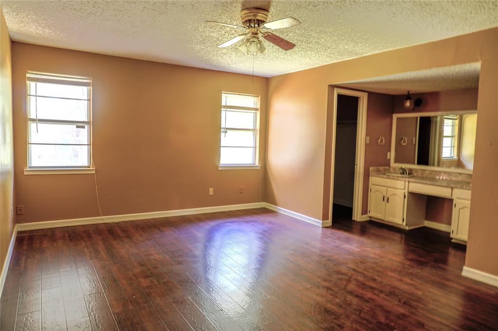 300 Coury Road Everman, TX 76140 - Photo 12 of 29 an empty room with wooden floor a ceiling fan and windows