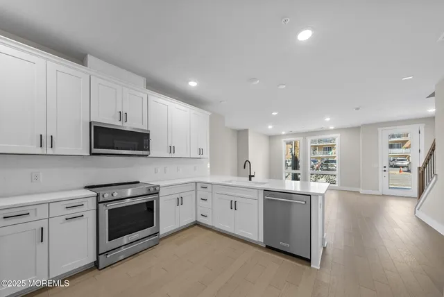 a kitchen with stainless steel appliances granite countertop a sink and cabinets with wooden floors