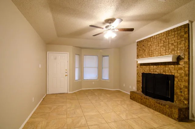 a view of empty room with fireplace and fan