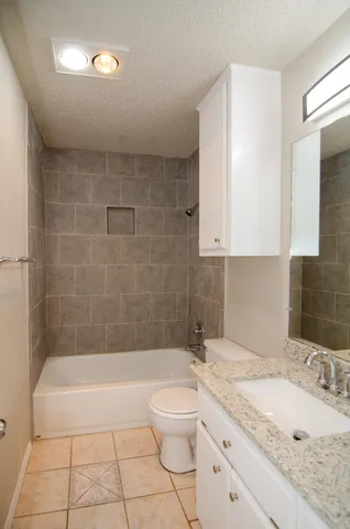 a bathroom with a granite countertop sink a toilet a mirror and bathtub