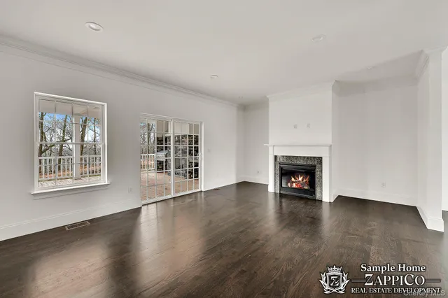 an empty room with wooden floor fireplace and windows