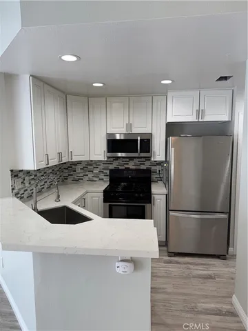 a kitchen with a sink a refrigerator and a stove top oven with wooden floor