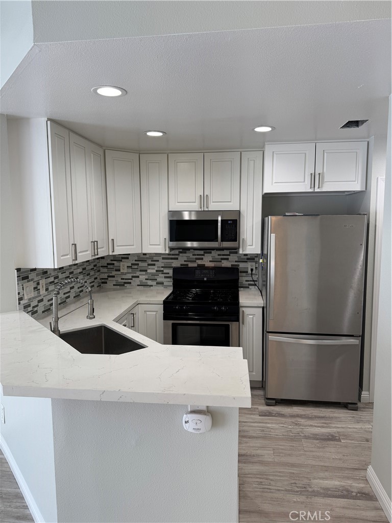 1730 Sinaloa Road Simi Valley, CA 93065 - Photo 12 of 38 a kitchen with a sink a refrigerator and a stove top oven with wooden floor