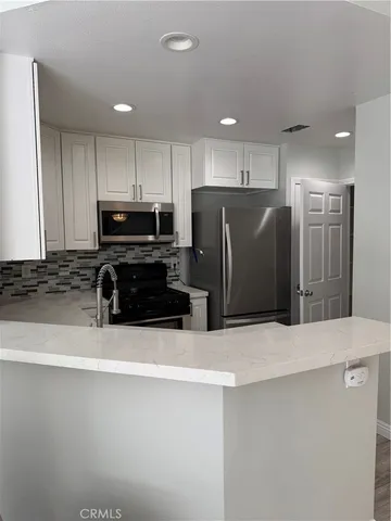 a kitchen with stainless steel appliances a refrigerator and a stove top oven