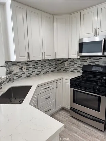 a kitchen with granite countertop a stove sink and cabinets