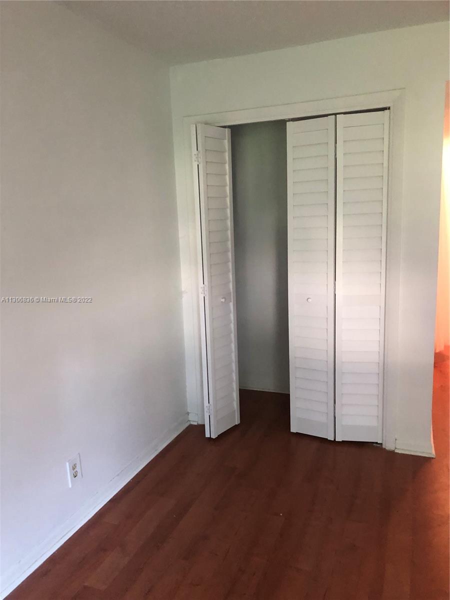 250 Gate Road, Unit 153 Hollywood, FL 33024 - Photo 17 of 19 an empty room with wooden floor and mirror