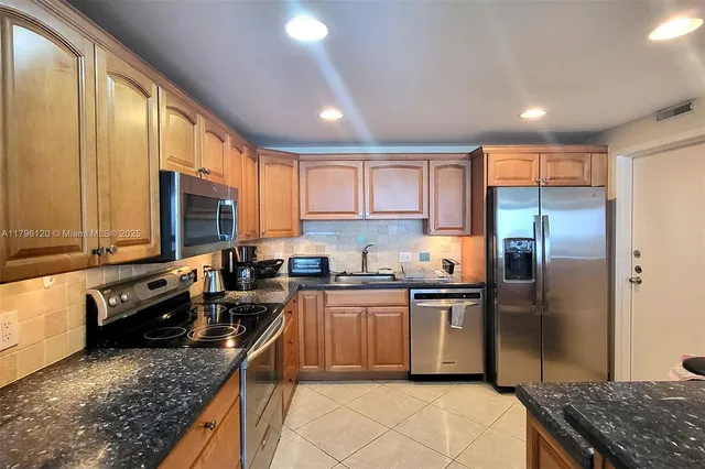 a kitchen with stainless steel appliances granite countertop a stove a sink and a refrigerator