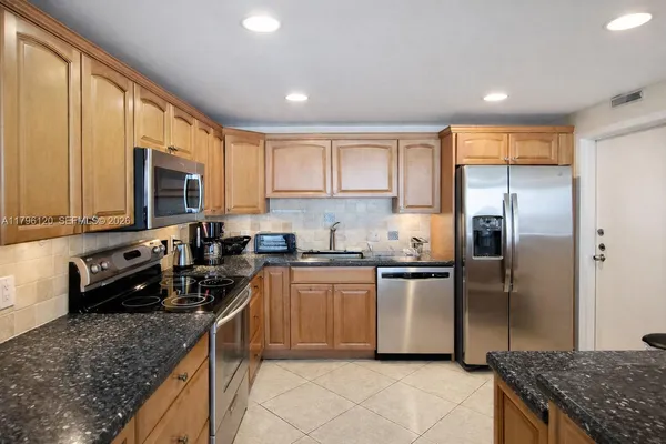 a living room with furniture a flat screen tv and a refrigerator