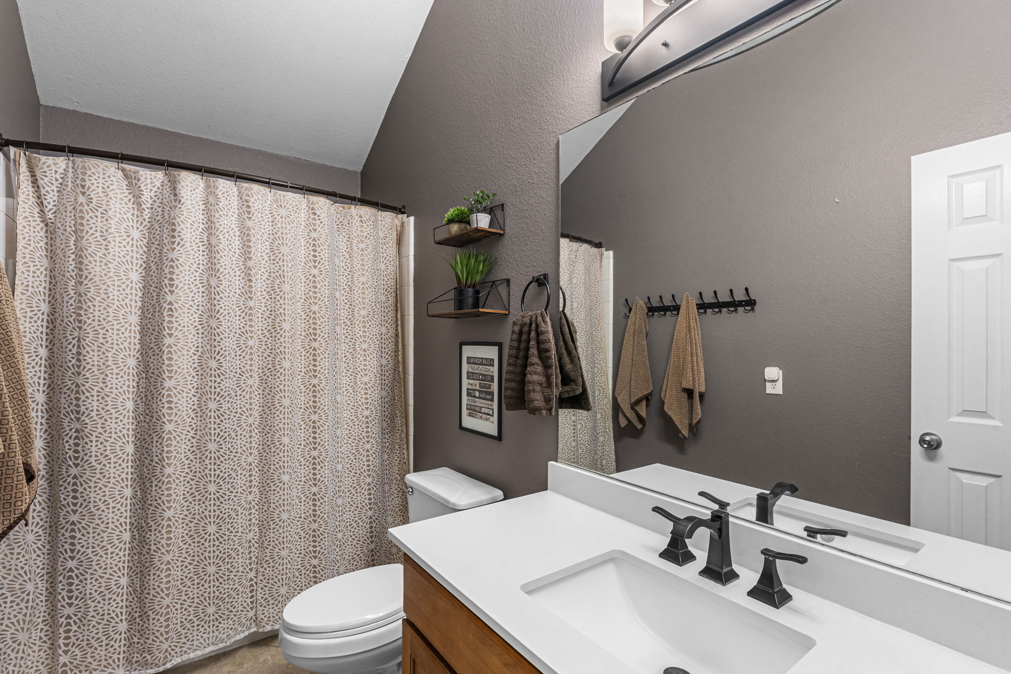 454 Fall Circle Kyle, TX 78640 - Photo 26 of 39 A clean, modern bath with rich wall tones, a pristine vanity, and striking dark fixtures.