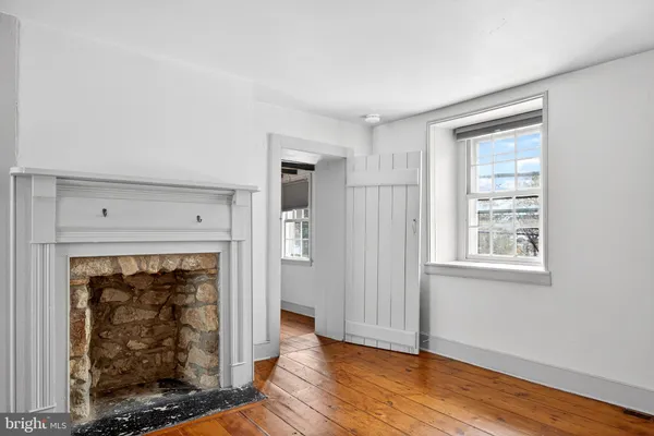 a view of an empty room with wooden floor fireplace and a window