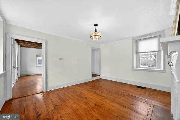 a view of an empty room with window and wooden floor