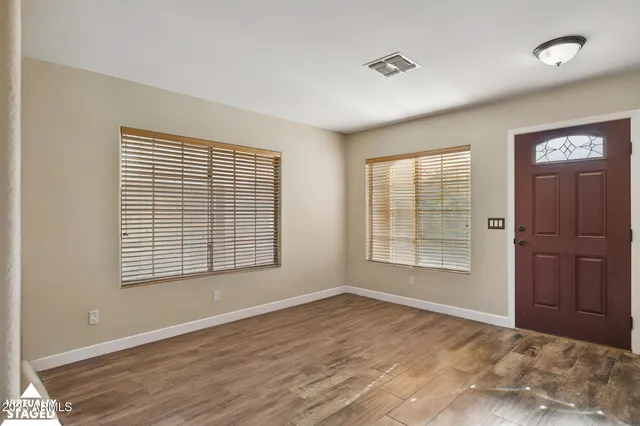 a view of an empty room with a window and wooden floor