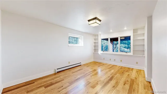 a view of an empty room with a window and wooden floor
