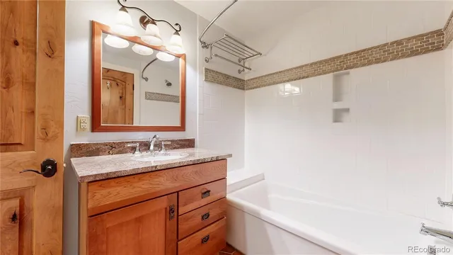 a bathroom with a bathtub sink vanity and mirror