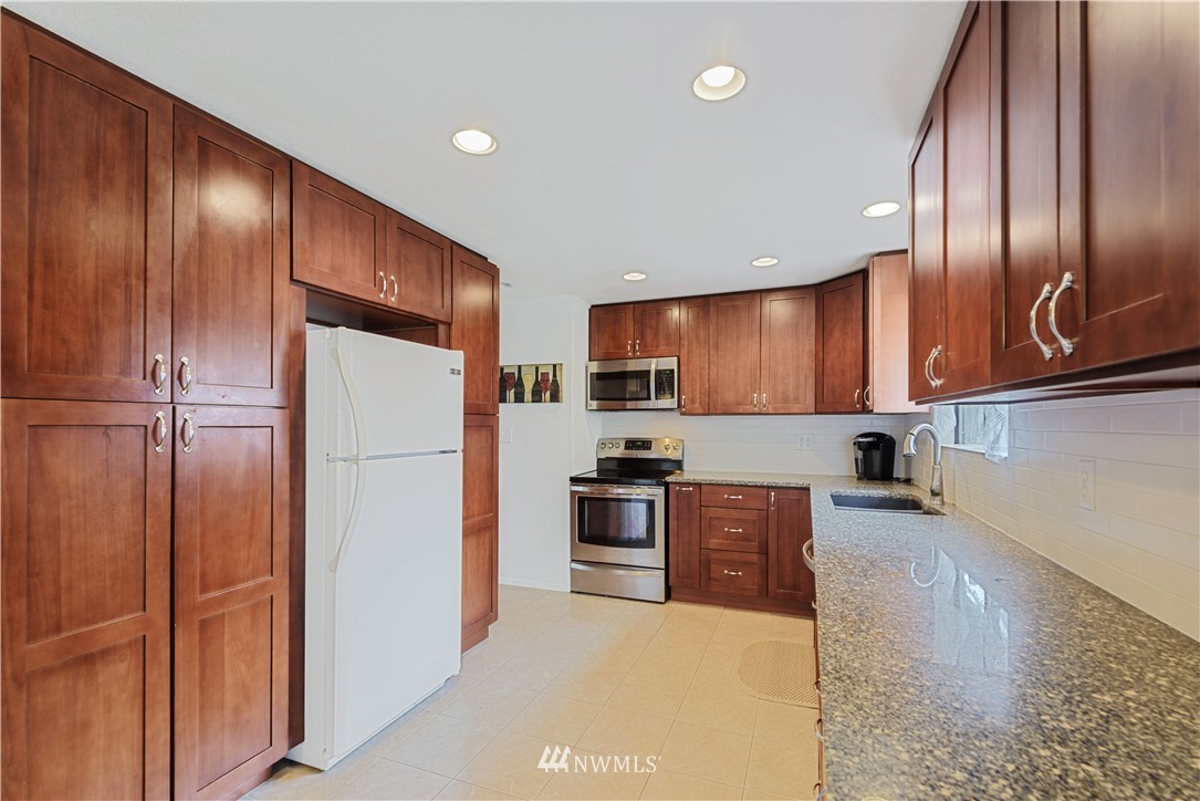 19910 Filbert Drive Bothell, WA 98012 - Photo 5 of 16 a kitchen with stainless steel appliances granite countertop a refrigerator a stove and a sink with wooden floor