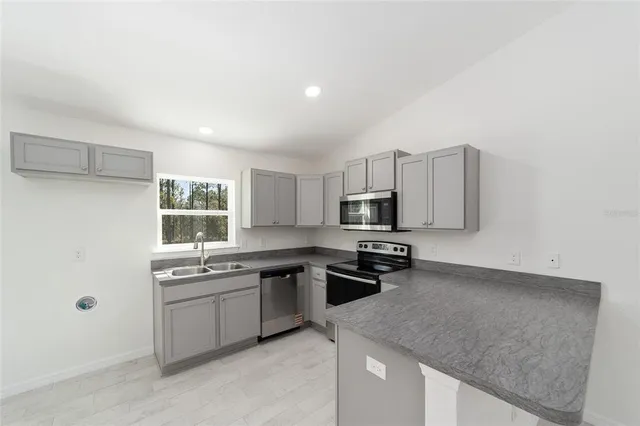 a kitchen with stainless steel appliances granite countertop a sink stove and microwave