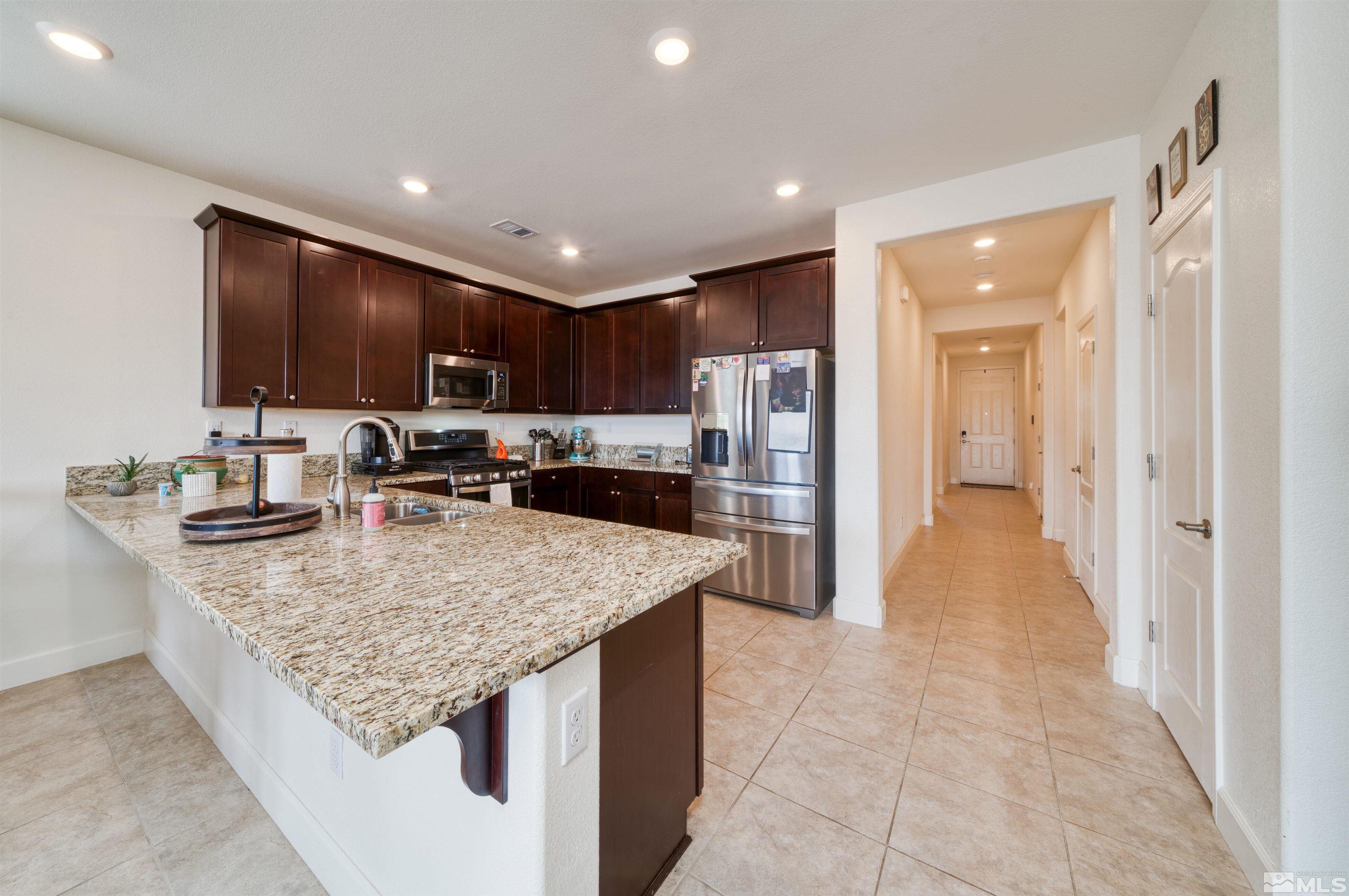 9784 Quartette Drive Reno, NV 89521 - Photo 8 of 18 a kitchen with stainless steel appliances granite countertop a sink refrigerator and cabinets