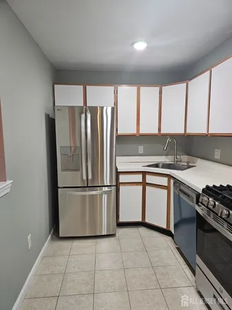 a large white kitchen with a sink and dishwasher a stove with wooden floor
