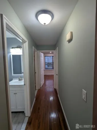a view of a hallway with wooden floor and a bathroom