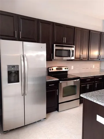 a kitchen with granite countertop a refrigerator and a stove top oven