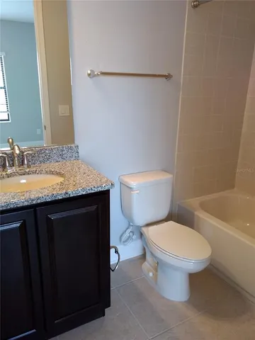 a bathroom with a granite countertop toilet sink and mirror