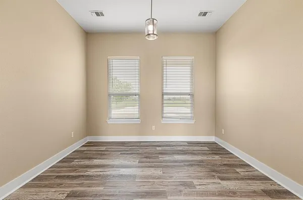 an empty room with wooden floor ceiling fan and windows