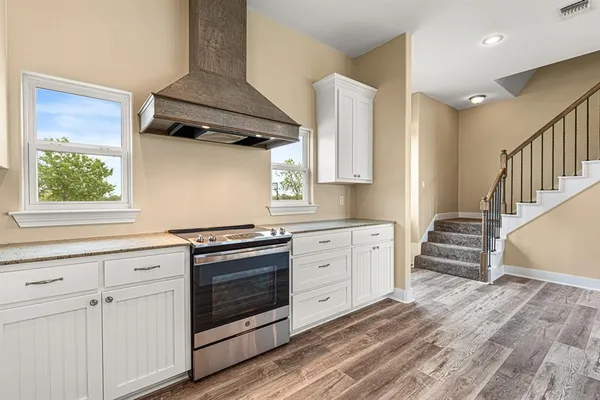 a kitchen with granite countertop a stove oven and white cabinets